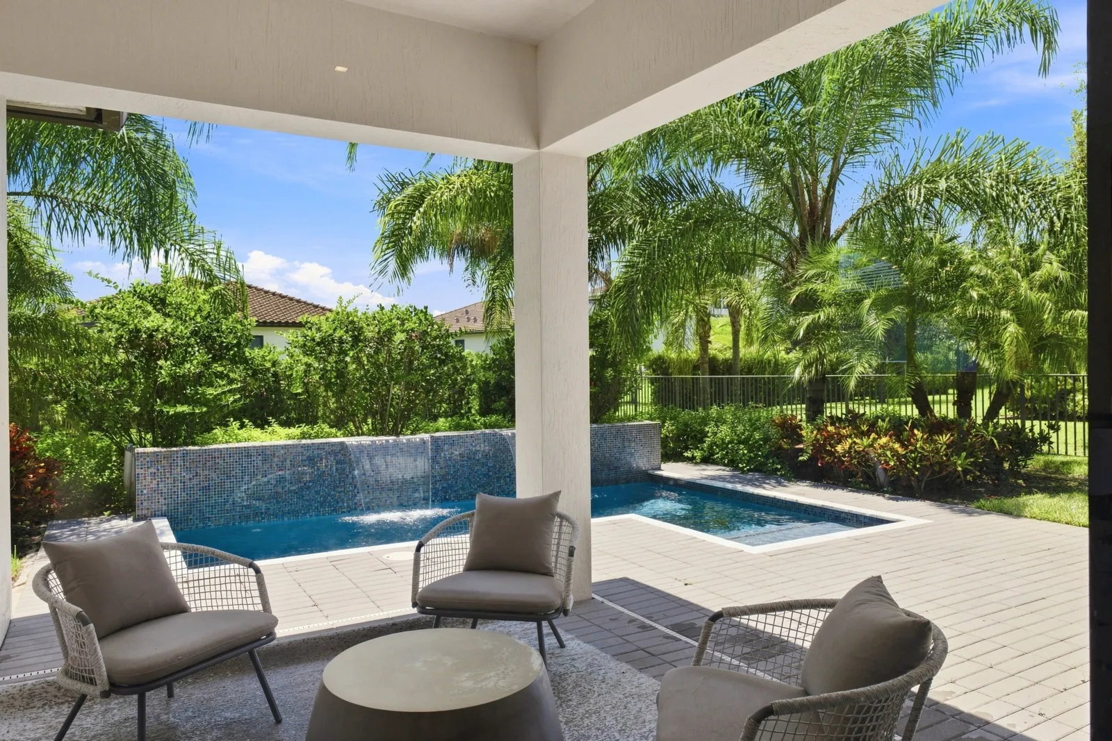 Covered patio seating overlooking a plunge pool and palms